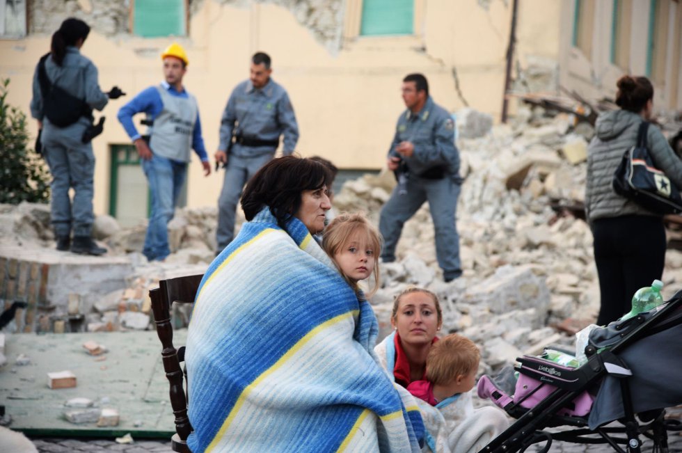 Várias famílias protegidas com cobertores descansam em uma rua de Amatrice.
