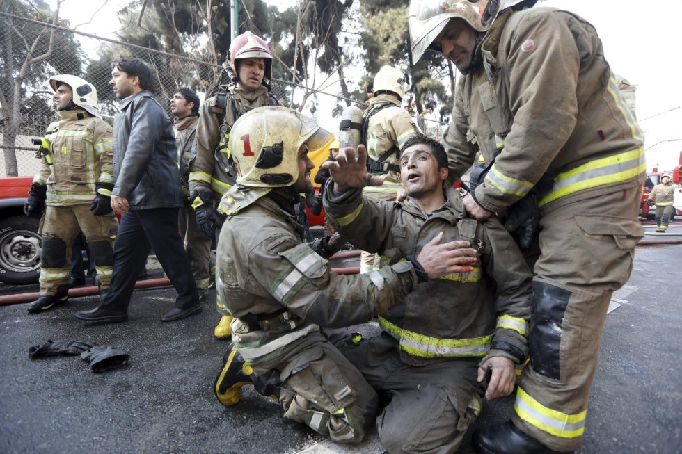 Bomberos iraníes trasladan a un compañero que lograron rescatar tras quedar atrapado entre los escombros del edificio Plasco de la capital de Teherán.