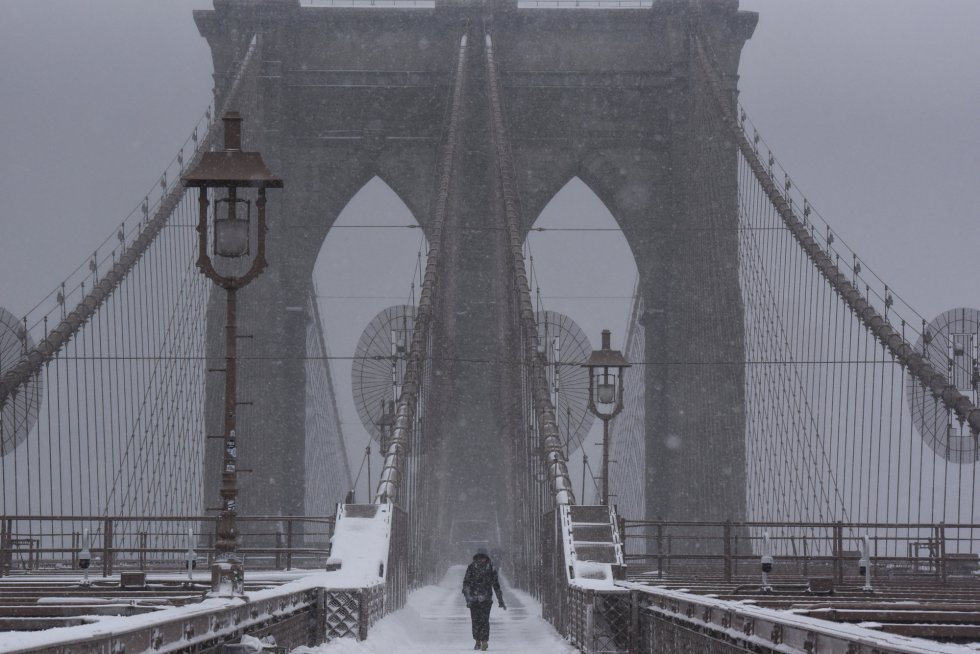 Una persona camina sobre el puente de Brooklyn durante la tormenta de nieve.