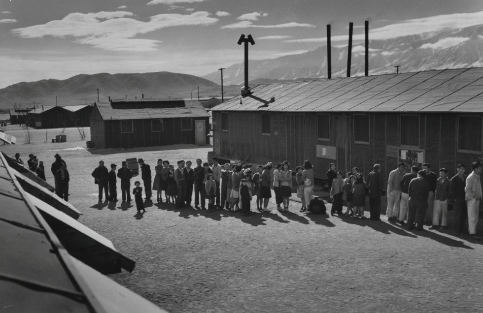 En los campos, a cada familia se le entregaron placas con un número grabado para cada miembro, que fueron utilizadas para identificarse. En la imagen, una larga cola de gente espera frente a un edificio del Centro de Reubicación de la Guerra 'Manzanar' en California, en 1943.