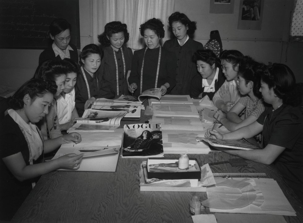 Una profesora mira junto a sus alumnas revistas de moda y patrones, en el Centro de Reubicación de Guerra 'Manzanar', en 1943, en California.