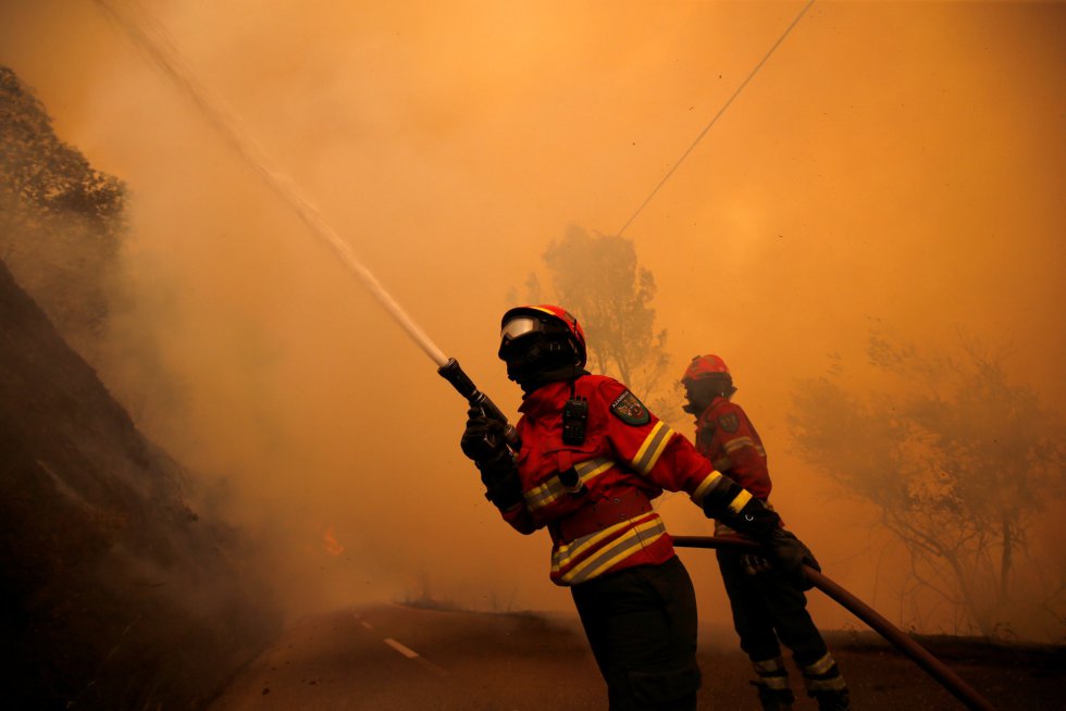 El incendio declarado este sábado en el centro de Portugal, que se mantiene activo en los distritos de Leiria y Coimbra, avanza hacia municipio de Góis, donde vecinos de varias aldeas han sido evacuados por las autoridades. En la imagen, una pareja de bomberos intenta sofocar el incendio en el pueblo de Sandinha, cerca de Góis.