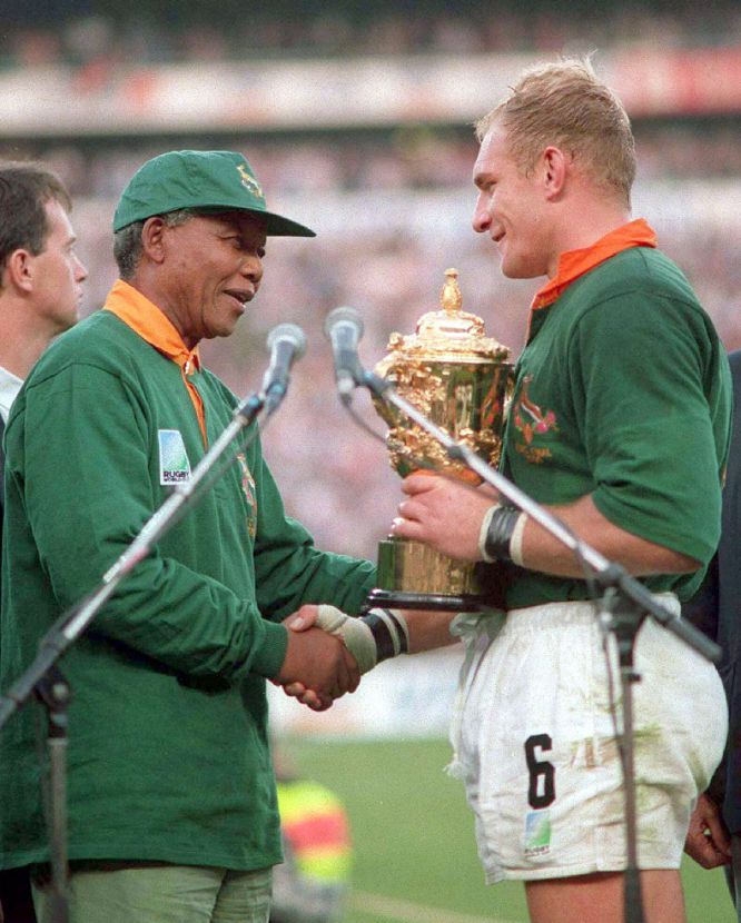 EL País:  El presidente de Suráfrica, Nelson Mandela, entrega la Copa del Mundo al capitán de la selección de Suráfrica, François Pienarr, tras ganar a Nueva Zelanda en Johannesburgo, el 24 de junio de 1995. (REUTERS) 