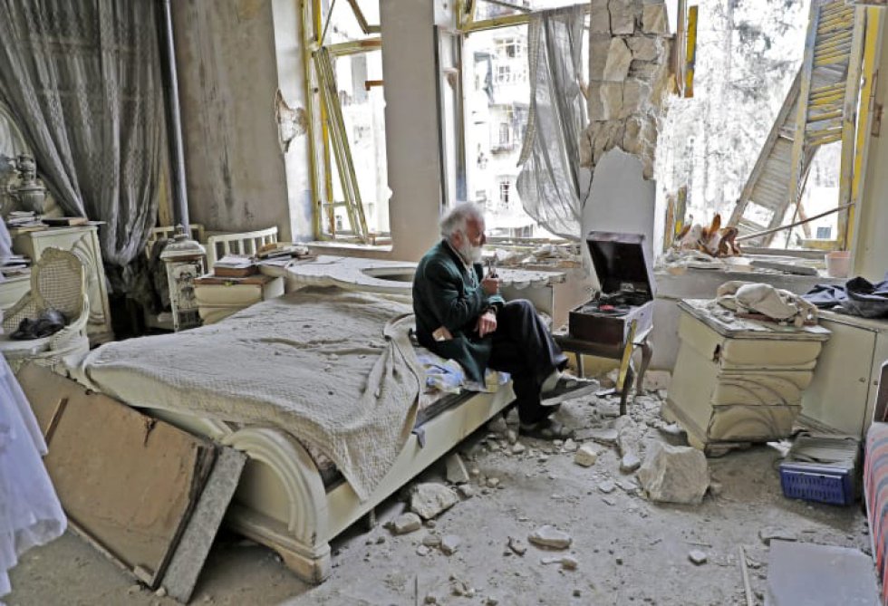 Mohammed Mohiedin Anis, de 70 anos, fuma um cachimbo sentado em seu quarto rodeado de escombros enquanto escuta músicas em Aleppo, a Síria, em 9 de março de 2017.