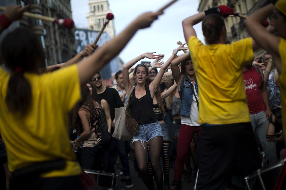 Un grupo de jóvenes baila en Barcelona tras la pancarta de cabecera que dice: '12-15M. El pueblo somos la solución. Volvemos a las plazas, seguimos en la calle'.