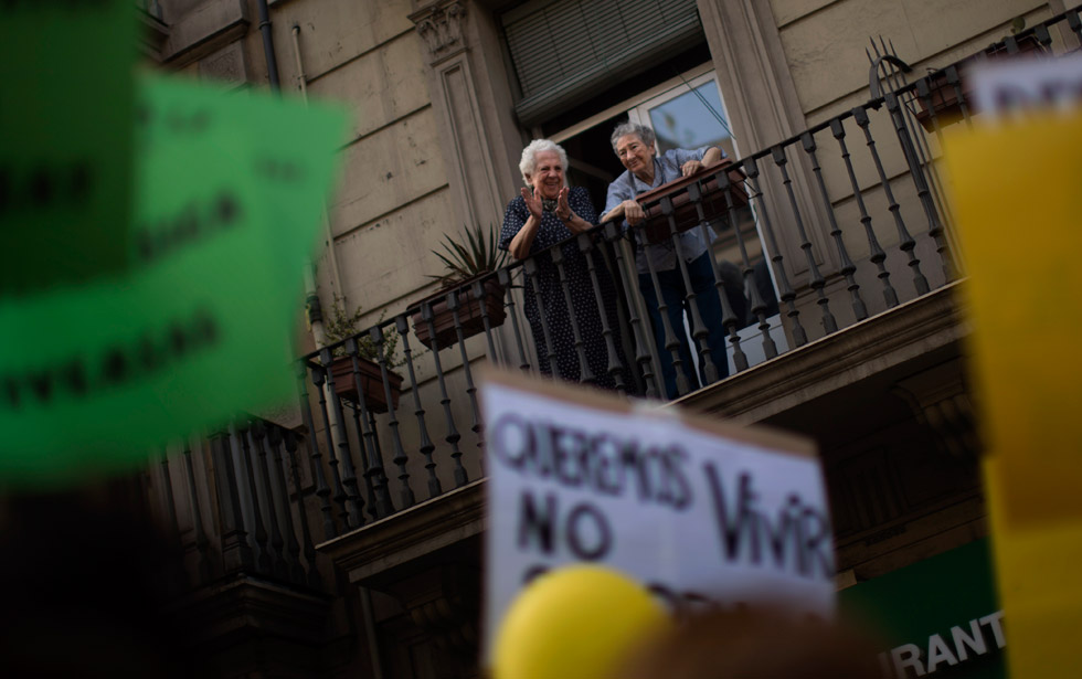 Dos mujeres animan desde el balcón a los manifestantes que transitan por las calles de Barcelona.