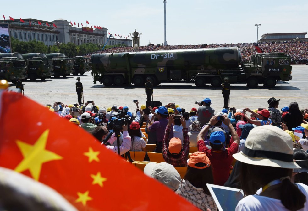 Ciudadanos que siguen la marcha militar aprovechan el paso de vehículos militares que transportan misiles DF-31A para hacer fotos.