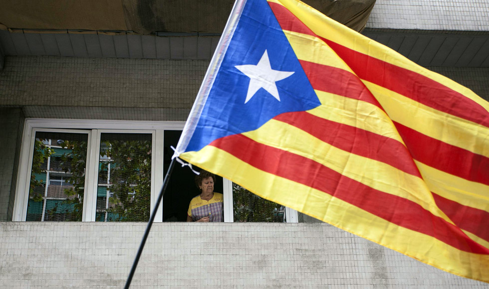 Una mujer mira desde una ventana la celebración de la Diada en Barcelona.