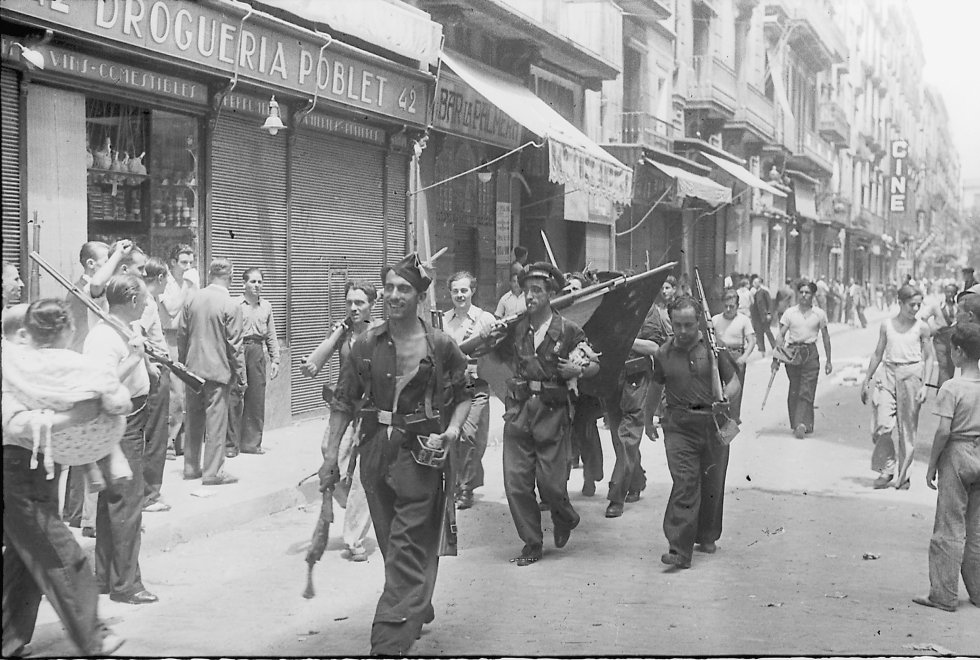 Milicianos en Barcelona. El primero lleva en una mano una lata de sardinas y en la otra una pata de jamón.
