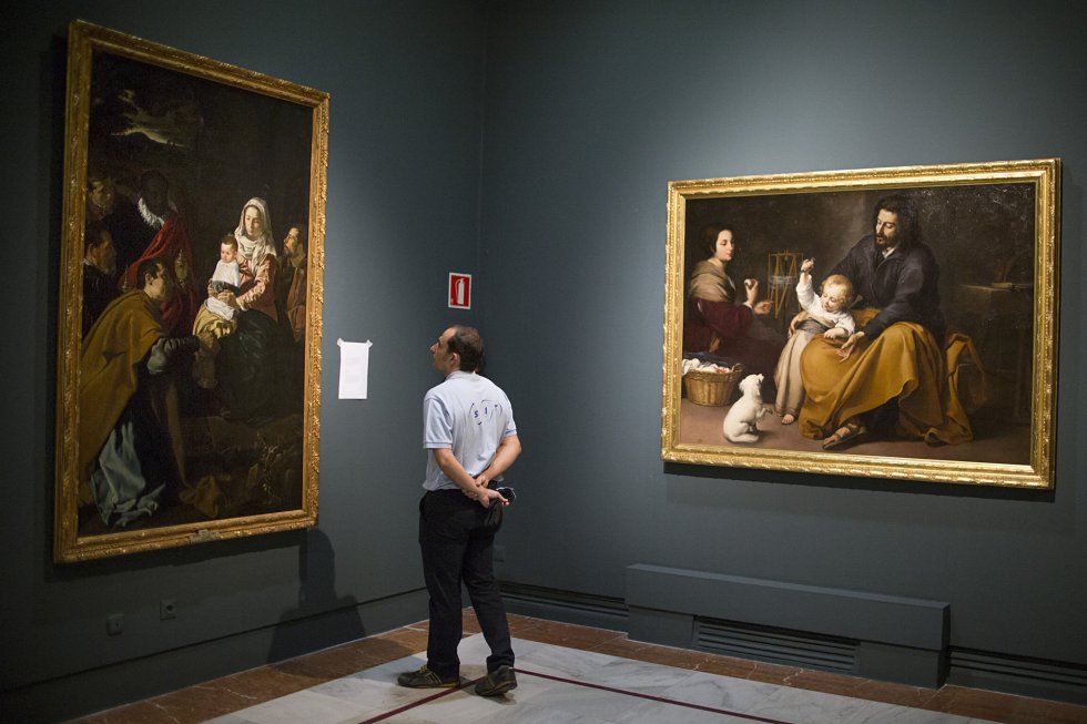 Un técnico mira 'La sagrada familia del pajarito', de Murillo, y 'Adoración de los Reyes', de Velázquez, en la Fundación Focus.