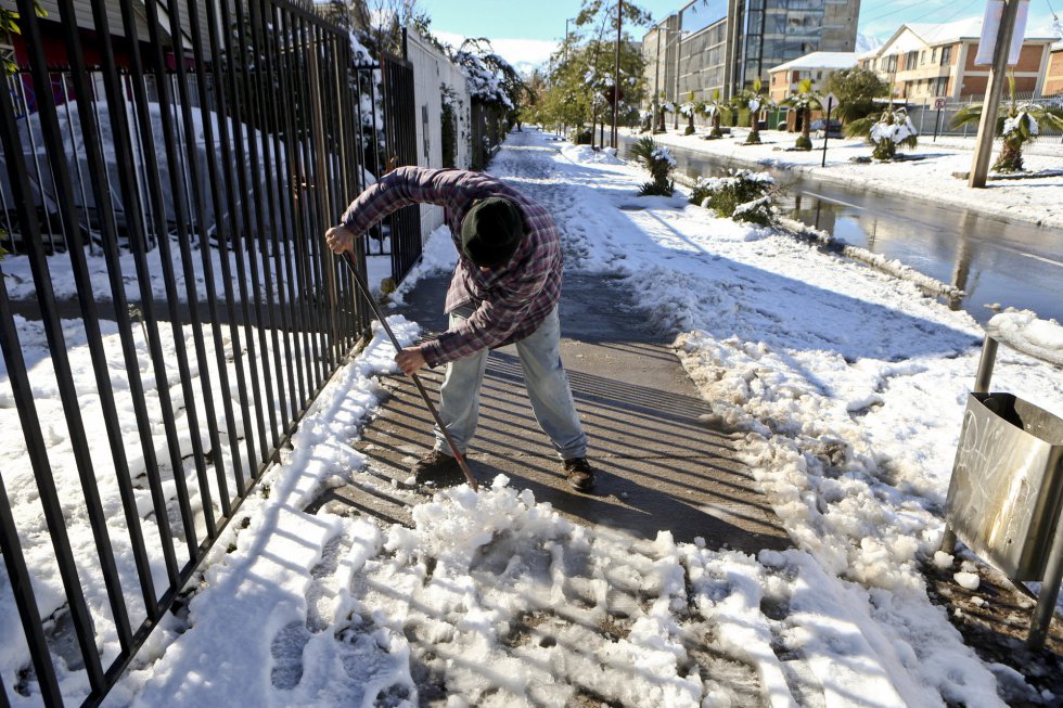 Un hombre limpia la nieve y el hielo de una acera a las puertas de una casa en Santiago, Chile, el 15 de julio de 2017.