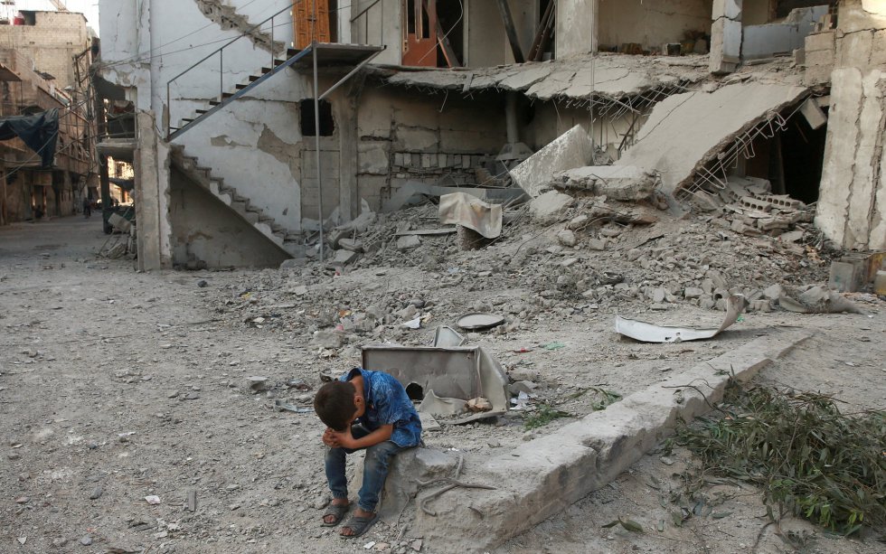 Un niño junto a escombros de edificios dañados por bombardeos en Arbin, cerca de Damasco, Siria.