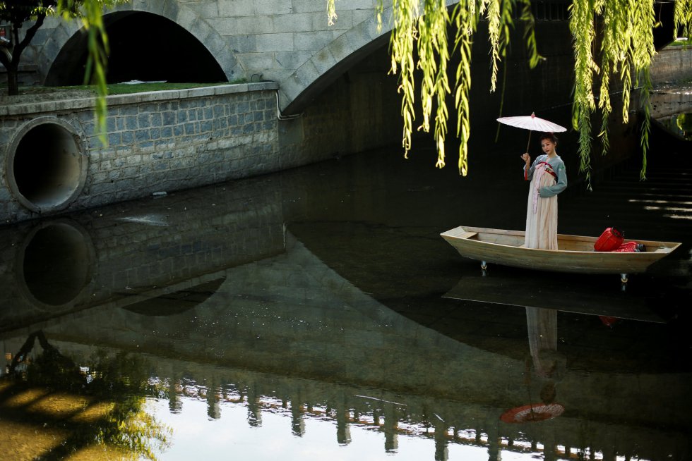 Una modelo posa subida a un barco en un canal poco profundo durante una sesión de fotos en un parque público en Pekín (China). 