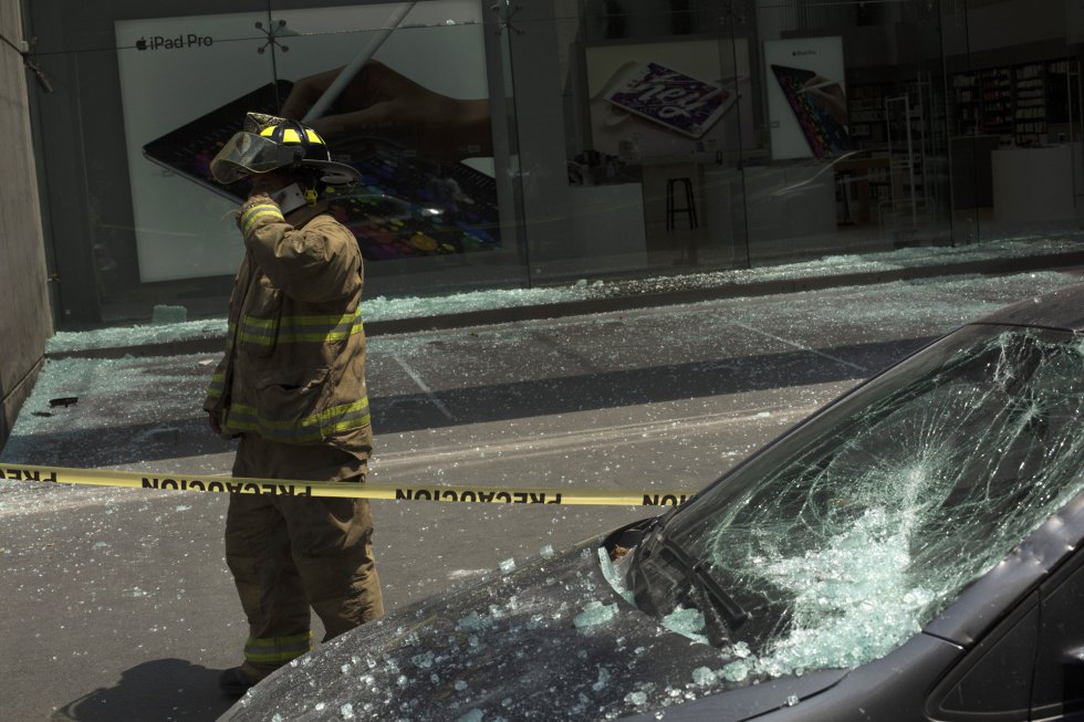 Un bombero junto a un coche dañado por el terremoto en Ciudad de México.