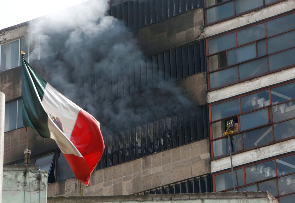 Un bombero descansa junto a un edificio del que sale humo tras el terremoto en Ciudad de México. 