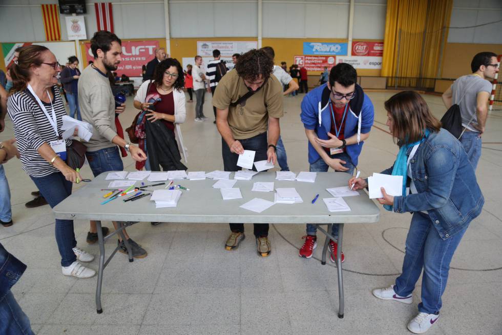 Un grupo de ciudadanos preparan su voto en el Pavelló Municipal Palau de Girona.