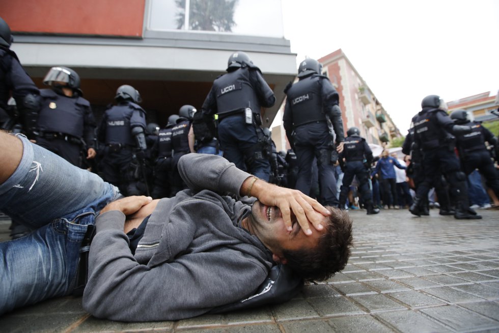 Un hombre cae al suelo durante la carga policial en la escola Mediterránea de la Barceloneta (Barcelona).