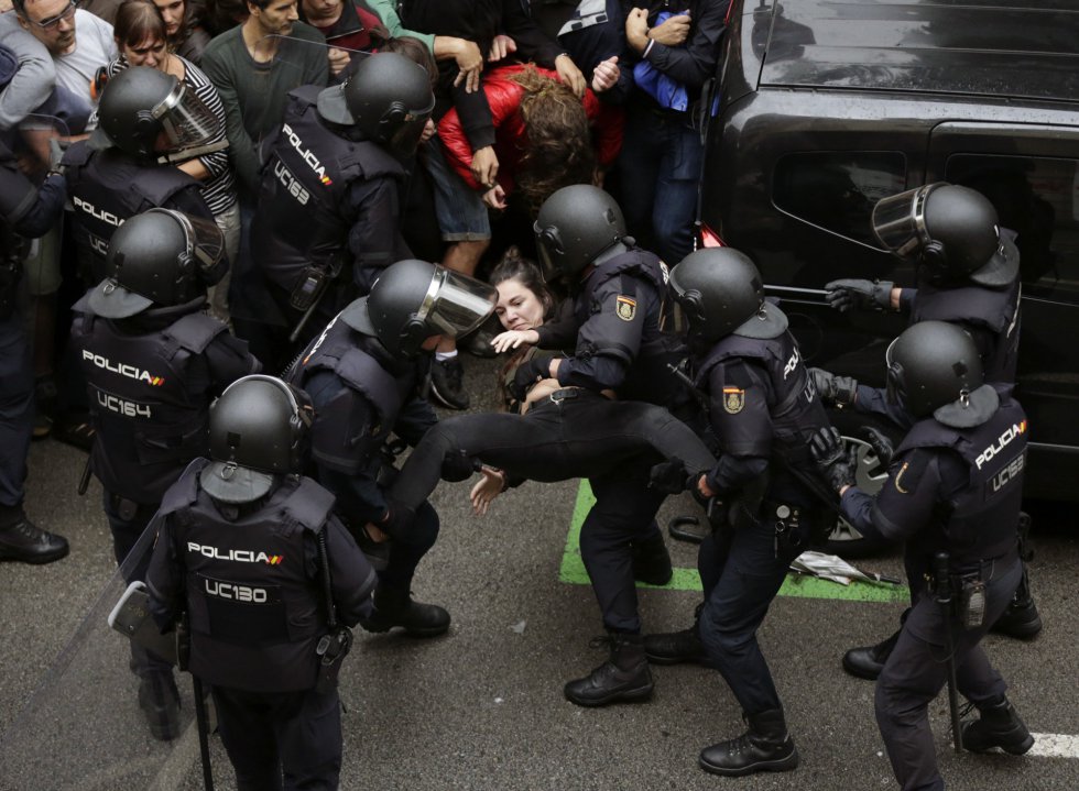 Agentes antidisturbios expulsan del perímetro de seguridad a una joven frente al colegio Ramón Llull de Barcelona.