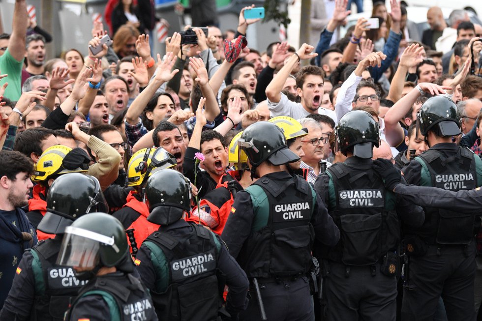 Un grupo de bomberos se coloca entre manifestantes y Guardia Civil fuera de una mesa de votación en San Julià de Ramis, Gerona.