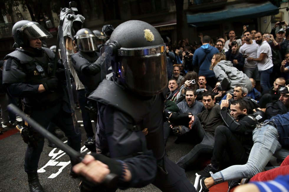 La Policía Nacional intenta desalojar a los simpatizantes del referéndum que se sientan en una calle de Barcelona.