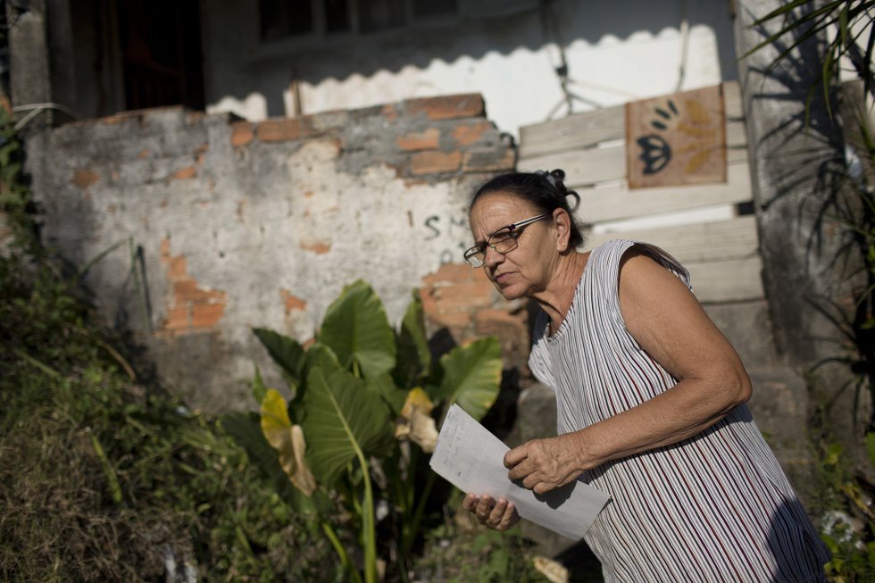 María de Pena Souza, de 59 años, vive con su hijo de 24 años en una pequeña casa con techo de zinc en la favela de Lins, al oeste de Río. Quieren mudarse porque la casa se encuentra en una colina empinada que es propensa a deslizamientos de tierra que pueden ser mortales. Pero su hijo no ha podido encontrar trabajo desde que terminó su servicio militar hace unos años.