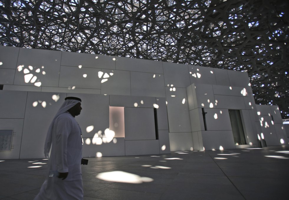 Un funcionario de Emiratos Árabes Unidos camina bajo la cúpula del Louvre de Abu Dabi. La majestuosa cúpula de 180 metros de diámetro y 7.500 toneladas que cubre el complejo está perforada por estrellas de formas irregulares, que dejan entrar el sol creando reflejos caprichosos en el patio en torno al que se articula el museo.