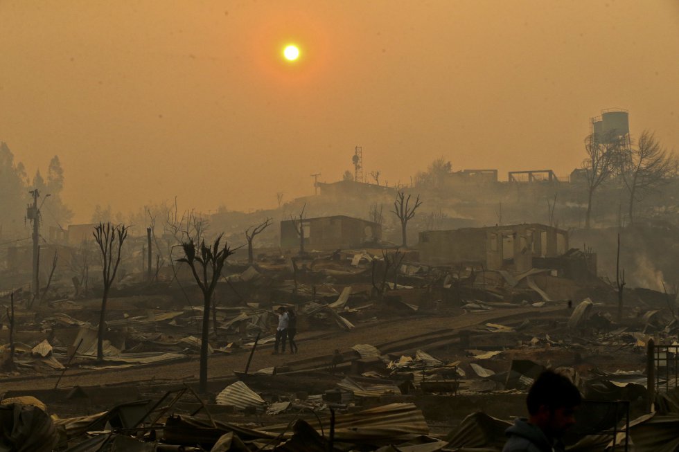 Una pareja pasea por su barrio destruido por los incendios en Santa Olga (Chile), el 26 de enero de 2017. La comunidad fue destruida por el fuego en los peores incendios que ha sufrido el país, según las autoridades.