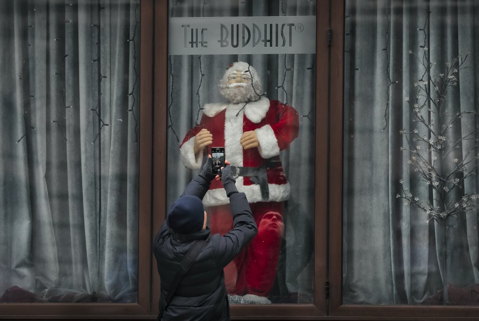Un hombre toma imágenes de un gran maniquí de Papá Noel, decorando un escaparate en Bucarest, Rumania.