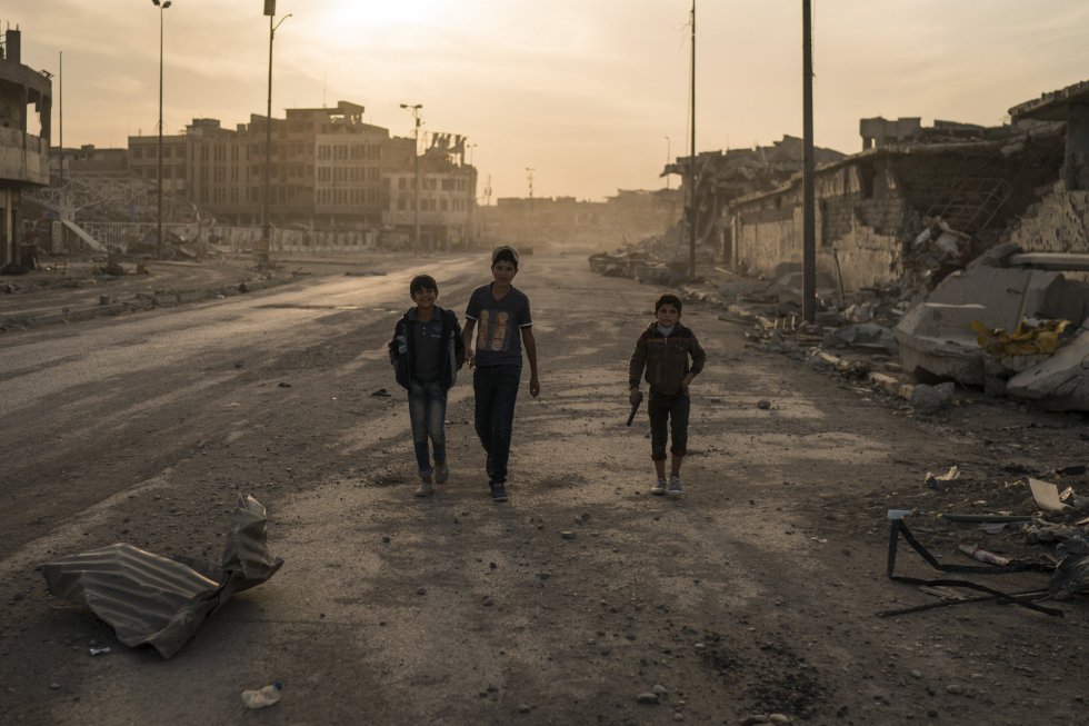 Un grupo de chicos, uno de ellos con un arma, pasean por las calles vacías del a Ciudad Vieja de Mosul. El coste de reconstruir tras la expulsión del Estado Islámico será enorme. Bagdad calcula que se necesitan cerca de 100 mil millones de dólares para la reconstrucción del país, los líderes locales de Mosul estiman que esa cantidad es necesaria sólo para reconstruir su urbe.