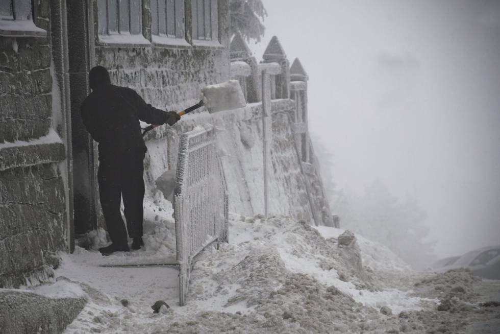 Un hombre retira la nieve de la puerta de una vivienda en el Puerto de Navacerrada, en la M-601, el 2 de febrero de 2018.
