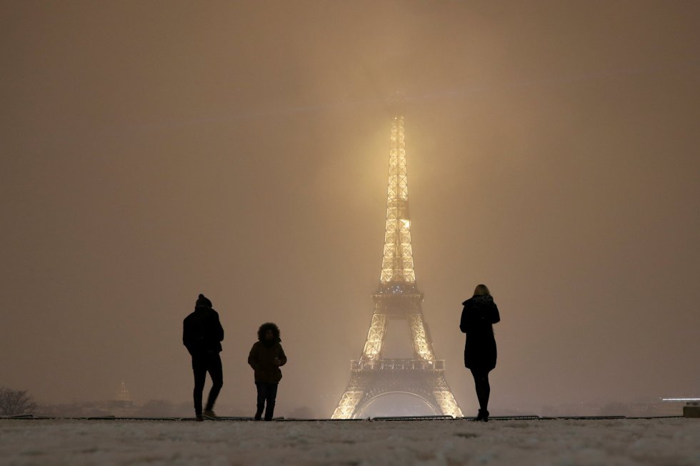 Turistas caminan sobre la nieve cerca de la Torre Eiffel en París (Francia).