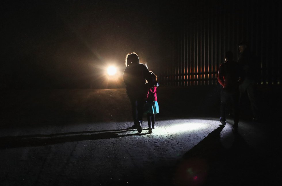 Una madre hondureña camina con sus hijos al lado de la valla fronteriza, la madre decidió entregarse a los agentes de la Patrulla Fronteriza ante los peligros y el cansancio que le asediaban. rn
