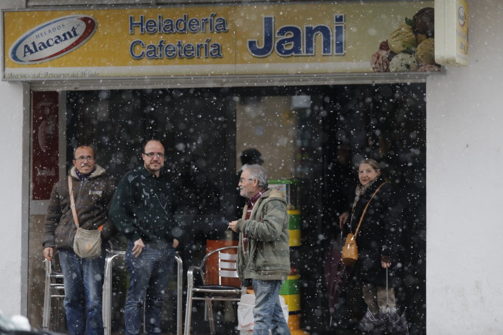Varias personas se resguardan de la nieve junto a una heladería de Utiel, donde la nevada ha obligado a suspender las clases, el 27 febrero.