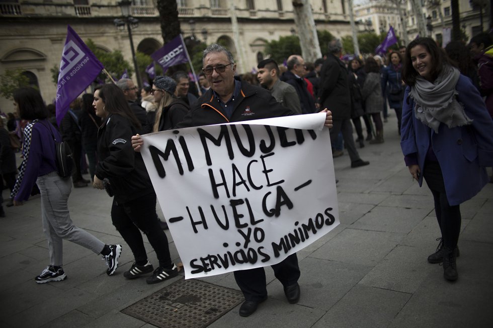 Un hombre sostiene un cartel con el lema "Mi mujer hace huelga... y yo servicios mínimos", en la concentración esta mañana en Sevilla.