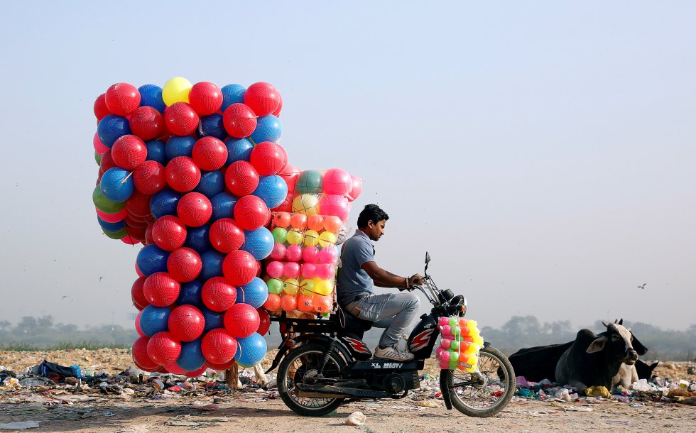 Un hombre lleva globos en su moto en Delhi (India).