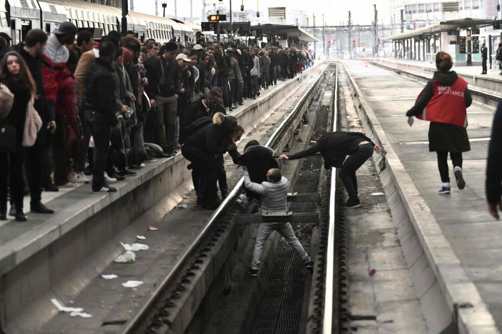 Varias personas ayudan a una mujer que se ha caído en las vías del tren de una estación de París (Francia), durante la huelga ferroviaria, el 3 de abril de 2018.