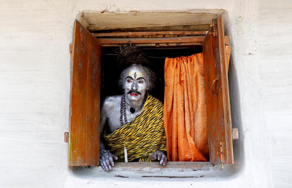 Un creyente vestido como el Dios hindÃº, Shiva, mira por la ventana mientras espera el inicio del festival Shiva Gajan a las afueras de Agartala (India).
