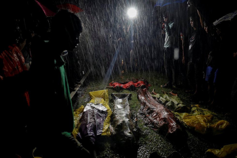 Pessoas se reúnem na chuva em torno dos corpos de alguns refugiados rohingyas que se afogaram na praia de Inani, perto do Cox's Bazar (Bangladesh), em 28 de setembro de 2017.