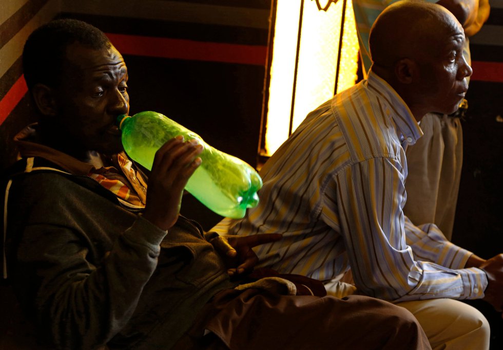 Un seguidor de la Iglesia de Gabola bebe una bebida casera de una botella de refresco durante un servicio en un bar en Orange Farm (Sudáfrica).