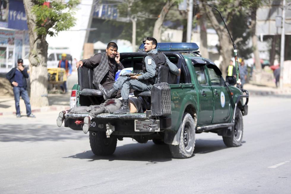 Personal de seguridad trasladan a una víctima tras el atentado en Kabul (Afganistán).