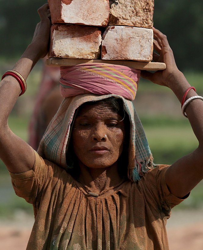 Una mujer india carga ladrillos sobre la cabeza mientras trabaja en una fábrica durante una tarde calurosa en la población de Nagda, a unos 55 kilómetros al norte de Kolkata (India).