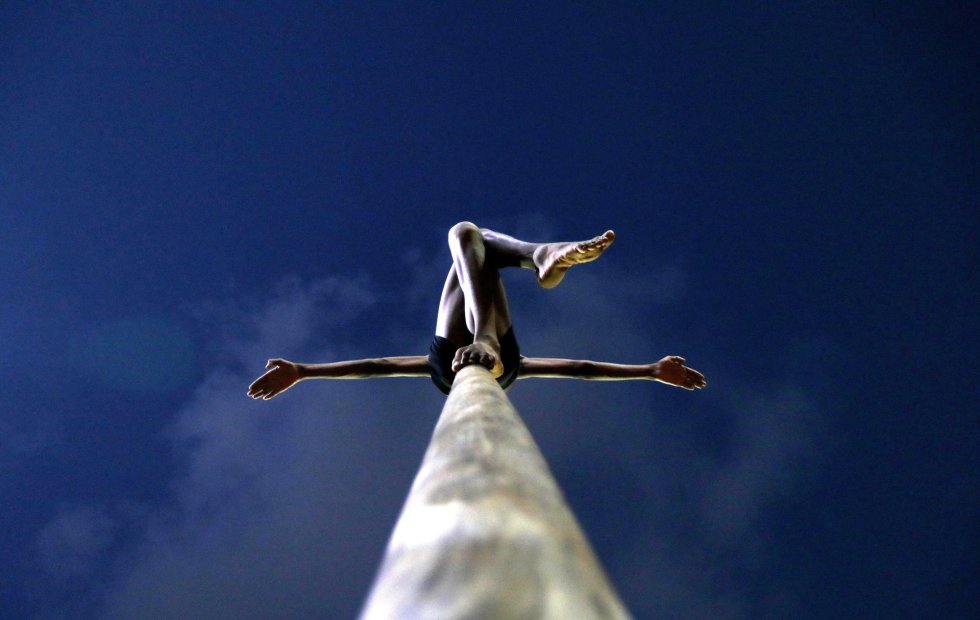 Un estudiante indio practica una postura mientras mantiene el equilibrio subido a un poste, durante un entrenamiento de Mallakhamba, en Bombay (India).