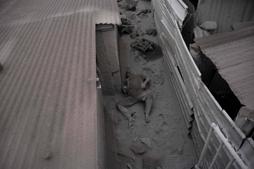 Una víctima yace en el suelo entre restos de ceniza lanzada por el volcán del Fuego, en San Miguel Los Lotes (Guatemala).