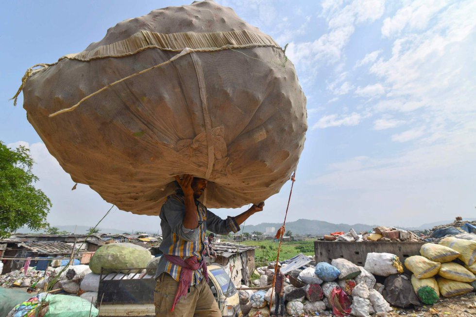 Un trabajador indio levanta este lunes un enorme saco lleno de botellas de plástico en uno de los mayores vertederos del noeste de la India.