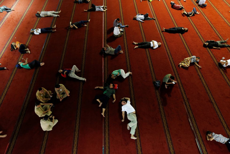 Un grupo de personas duerme en el suelo de la mezquita de Istiqlal mientras esperan el momento de la comida, en Yakarta (Indonesia).