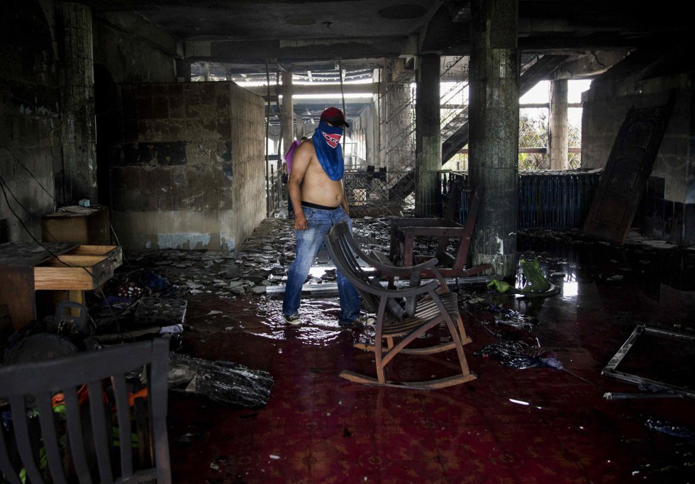 Un hombre limpia los escombros de una casa incendiada donde seis personas murieron durante las protestas en contra del gobierno de Daniel Ortega, en Managua (Nicaragua), el 16 de junio de 2018.