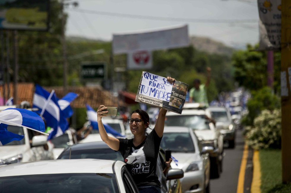 Una mujer sostiene un cartel en el que se lee "Que se rinda tu madre" -en respuesta a la petición de Ortega de que abandonaran las calles- durante una caravana en la ciudad de Masaya (Nicaragua) en apoyo a los manifestantes de esa ciudad que sufrieron los ataques de agentes antidisturbios y fuerzas sandinistas, el 13 de mayo de 2018.