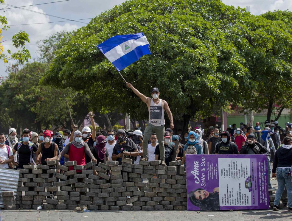 Un joven levanta una bandera de Nicaragua sobre una barricada, el 21 de abril de 2018, durante el cuarto día de protestas en Managua (Nicaragua).