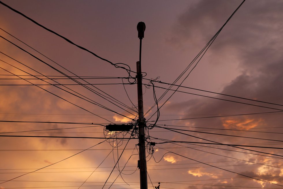 Un poste de alumbrado público y líneas eléctricas se ven al atardecer durante un apagón. En esta región se inició la explotación petrolera hace más de un siglo.