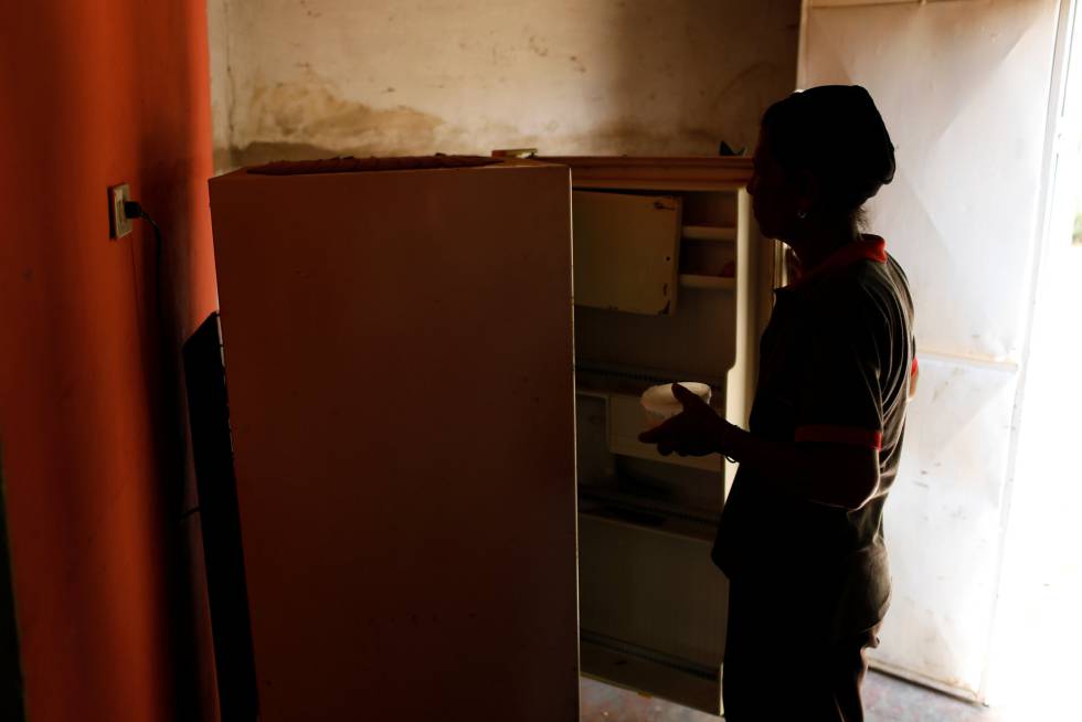 Matilde Balza saca a un recipiente de la nevera de su casa en el barrio marginal de Rafael Urdaneta, en Maracaibo, capital del estado de Zulia, en el noroeste del país. La mayoría de familias solo compran alimentos de consumo diario, ante la falta de abastecimiento eléctrico para mantener encendidos los refrigeradores.